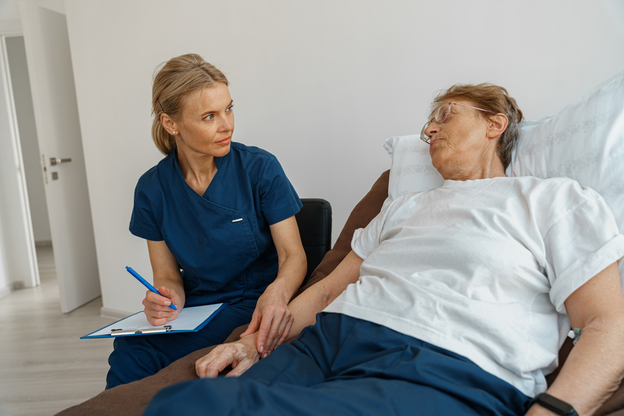 Une aide-soignante portant un stylo avec un porte-papier qui examine un patient