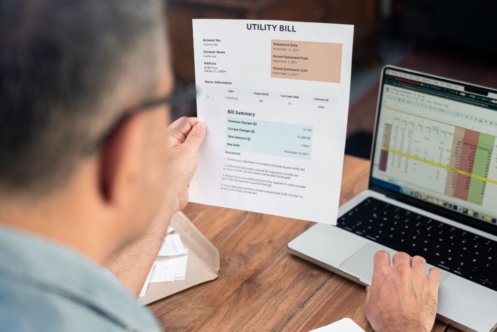 Un homme qui utilise excel pour faire une facture tout en regardant un modèle sur papier