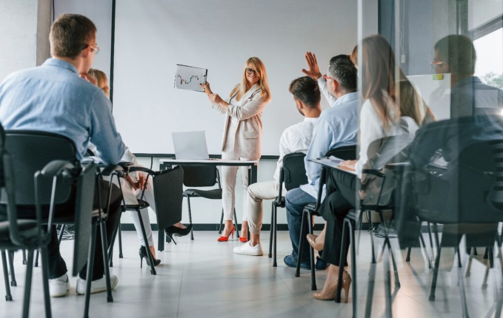 Une coach qui tient un papier devant des employés