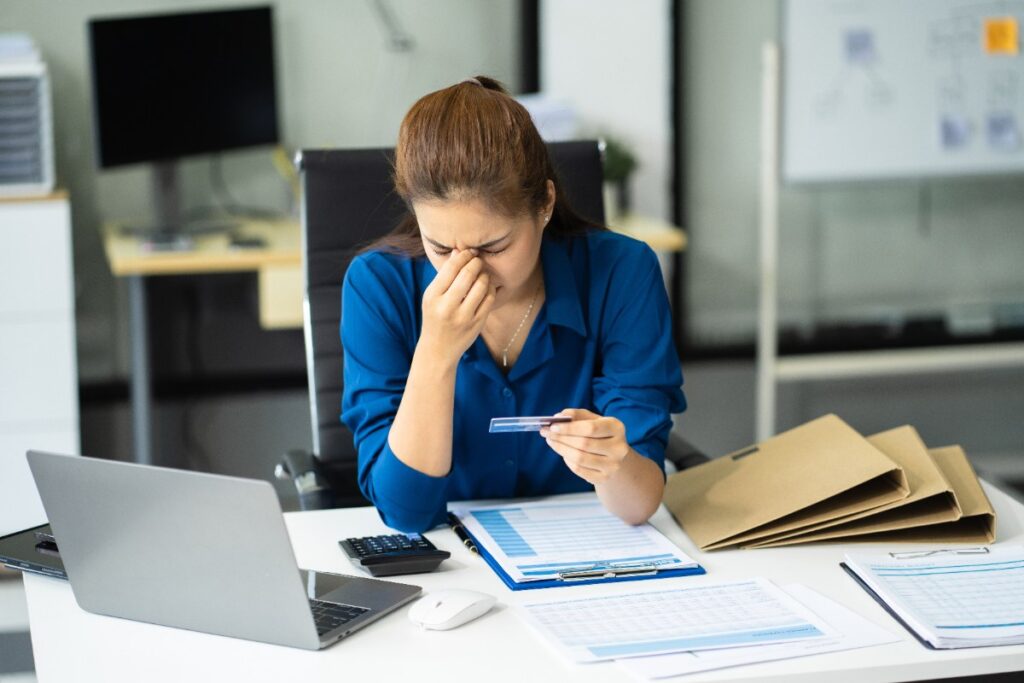 Une femme stressée tenant une carte de crédit dans son bureau