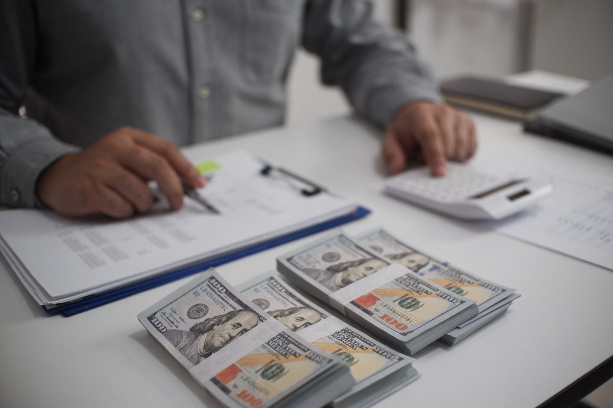 Une personne qui travaillle dans son bureau avec des documents et des monnaies sur la table