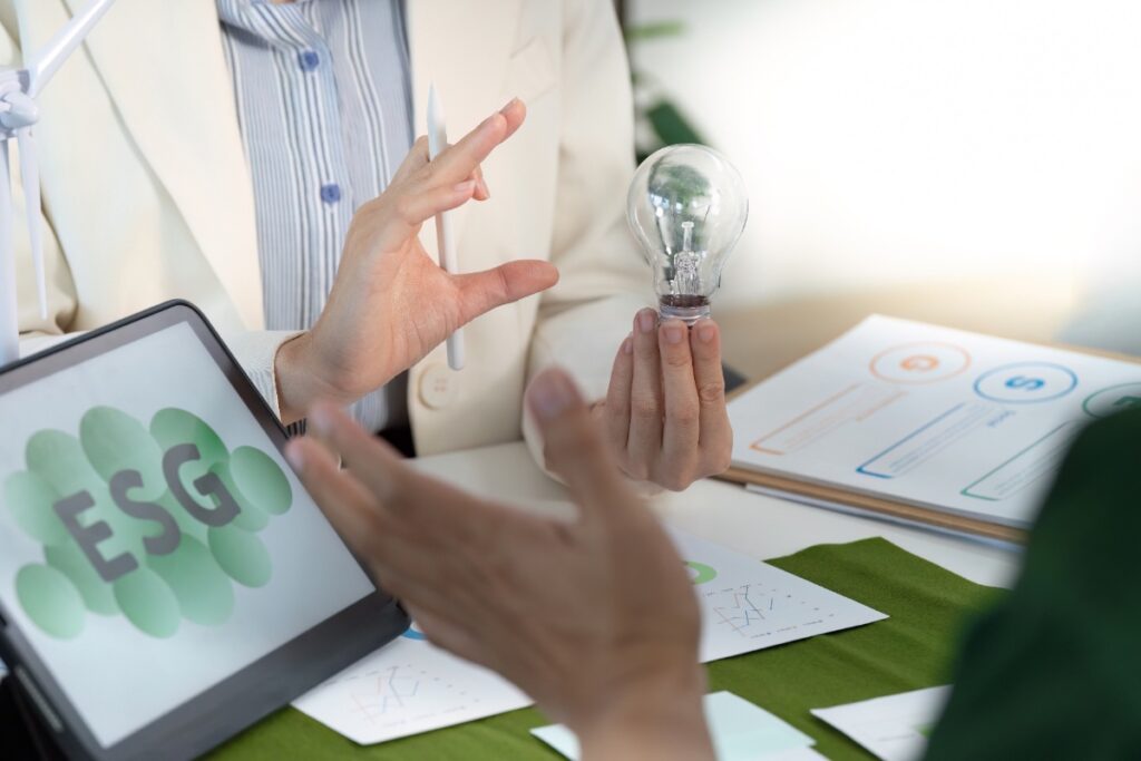 Des personnes qui discutent pour un analyse ESG avec une ampoule à la main 