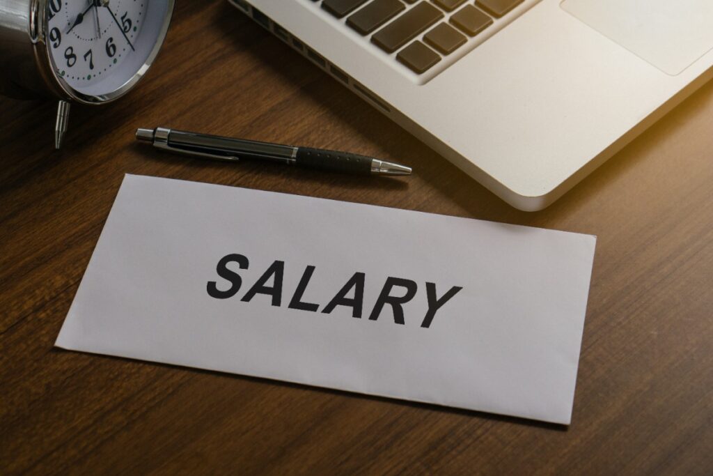 Salaire mis dans une enveloppe avec un stylo et un ordinateur portable sur la table