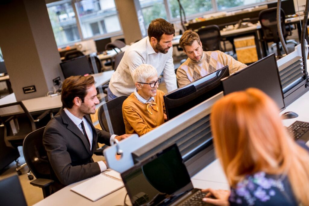 Des employés travaillant ensemble dans un bureau devant leur ordinateur