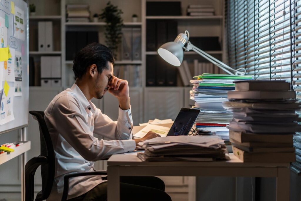 Un homme d'affaires stressé dans un bureau devant plusieurs dossiers
