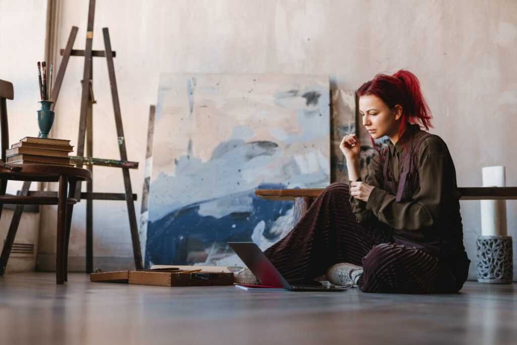Une jeune femme assise par terre qui peint un tableau