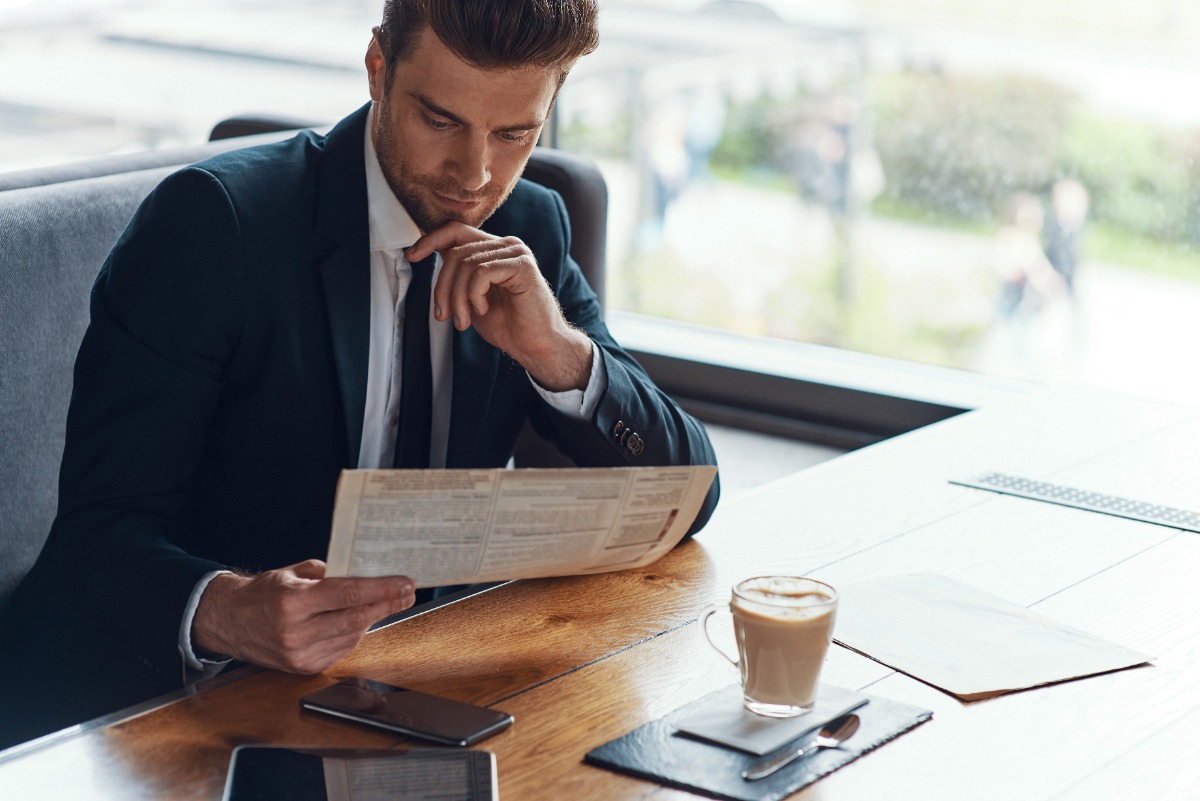 Un jeune homme d'affaires en costume lisant un document dans son bureau