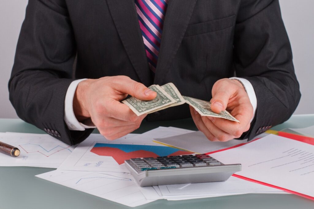 Un homme comptant de l'argent dans son bureau avec une calculatrice