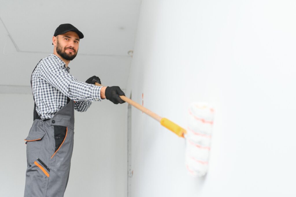 Un homme qui utilise un rouleau de peinture et peint le mur