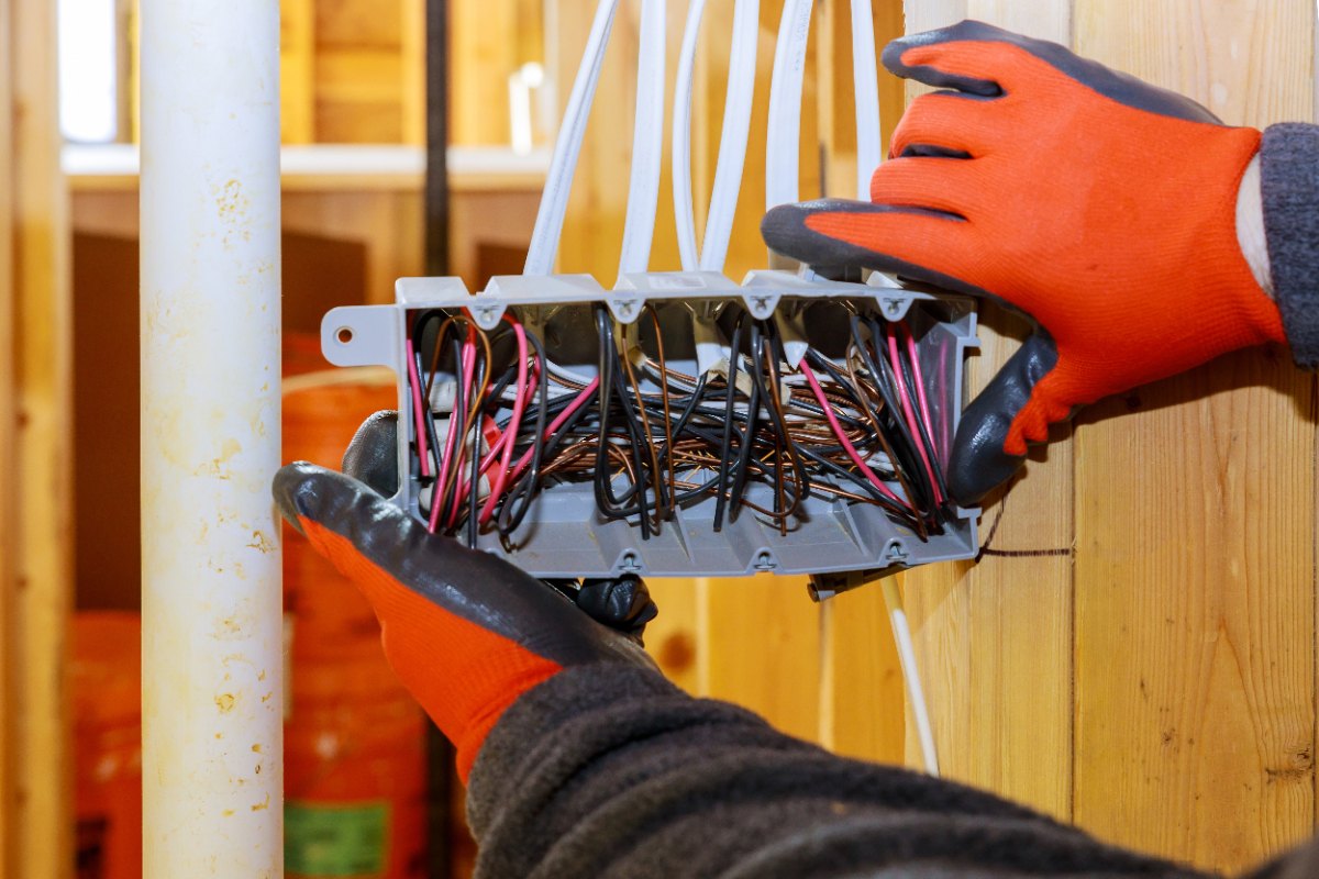 Un professionnel avec un gant faisant un câblage dans une boite éléctrique