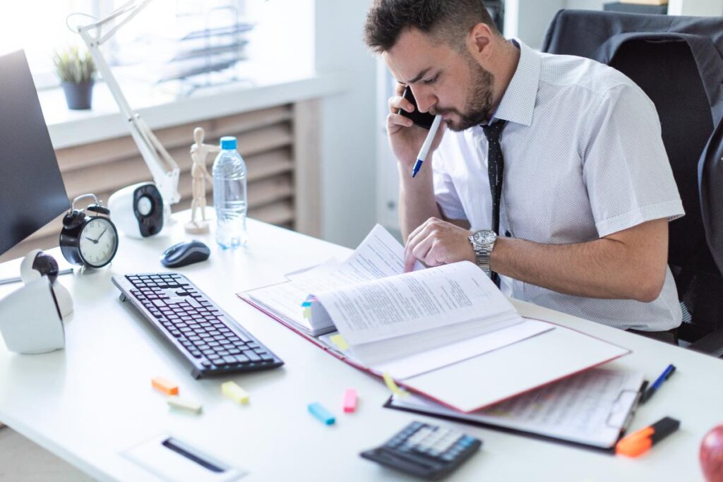 Un homme au téléphone regardant des documents sur la table