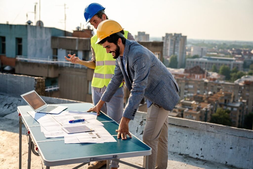 Des ouvriers vérifiant le progrès des travaux sur le chantier avec un ordinateur
