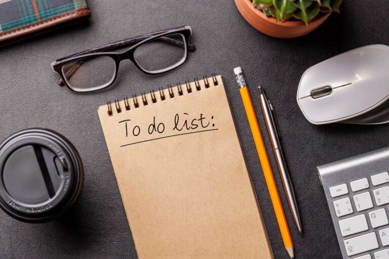 Un PC avec des fournitures de bureau, un café et un bloc note pour régider une liste de tâches
